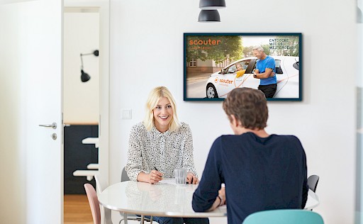 Blonde Frau und braunhaariger Mann sitzen sich an einem Tisch gegenüber