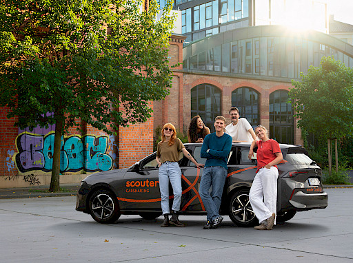 Gruppe junger Leute steht vor einem Carsharing Auto